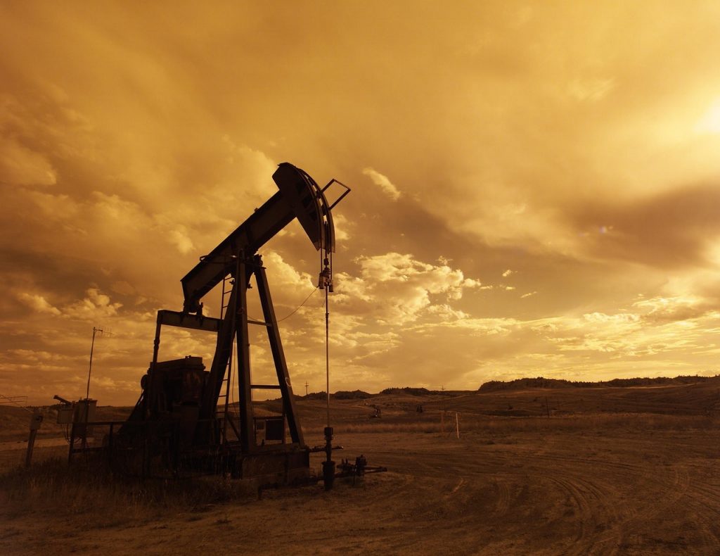 Energy oil pump jack in field at sunset